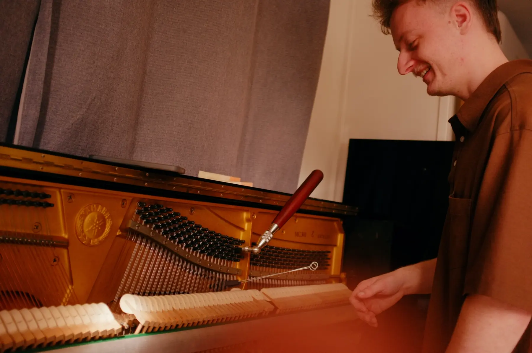 Reuben inspecting the action of an upright piano during a tuning appointment